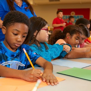 A group of children writing on paperDescription automatically generated